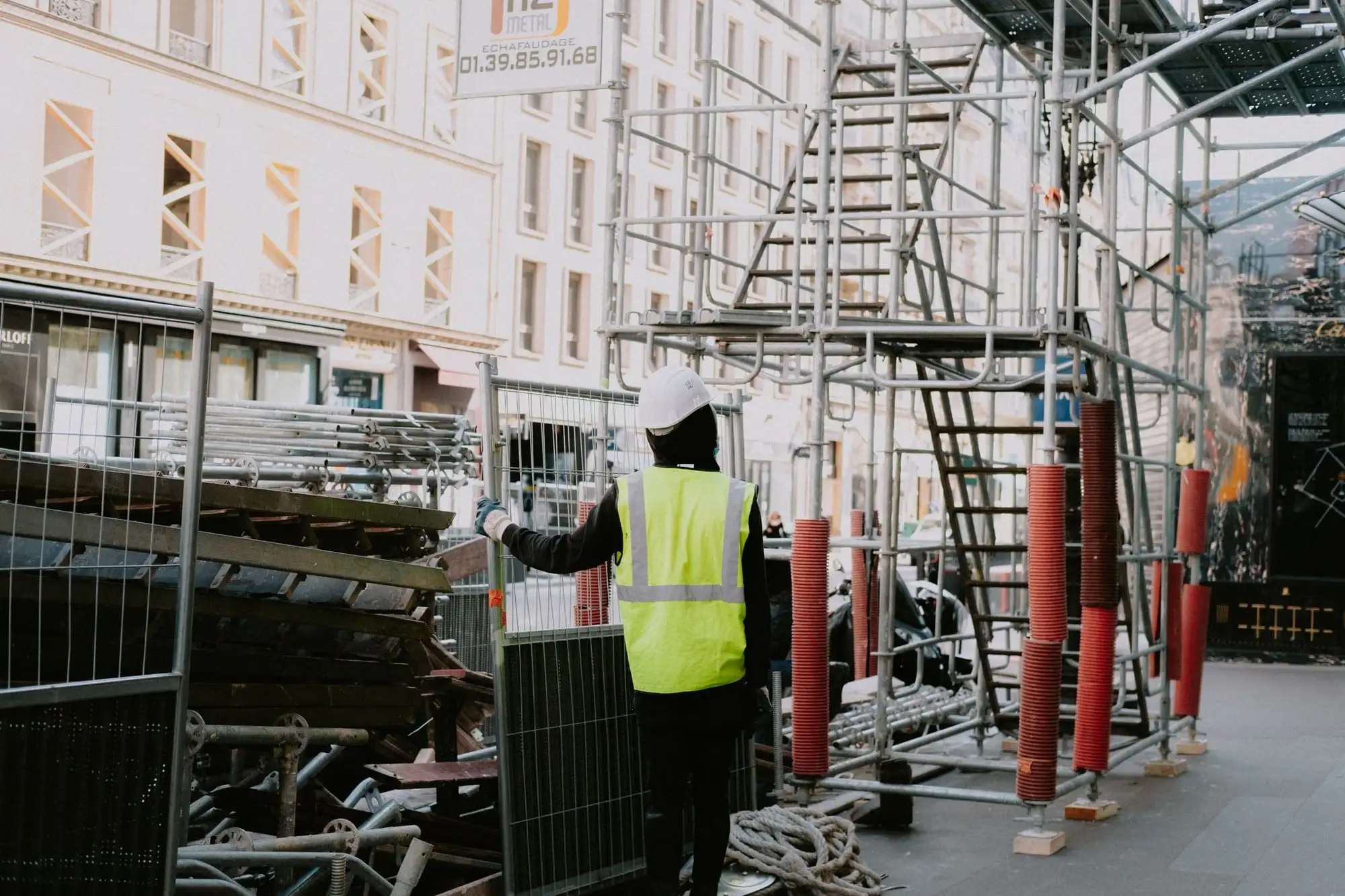 Person i refleksvest kontrollerer et stillads på en byggeplads